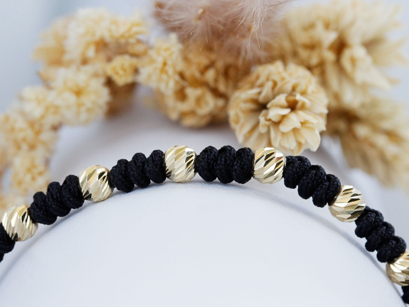 Złota bransoletka z diamentowanymi kulkami na czarnym sznurku