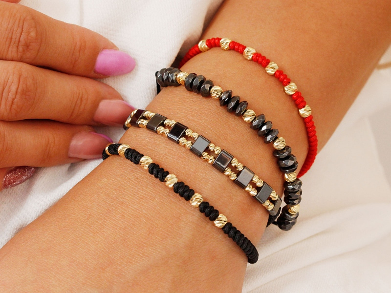 Złota bransoletka z diamentowanymi kulkami na czerwonym sznurku