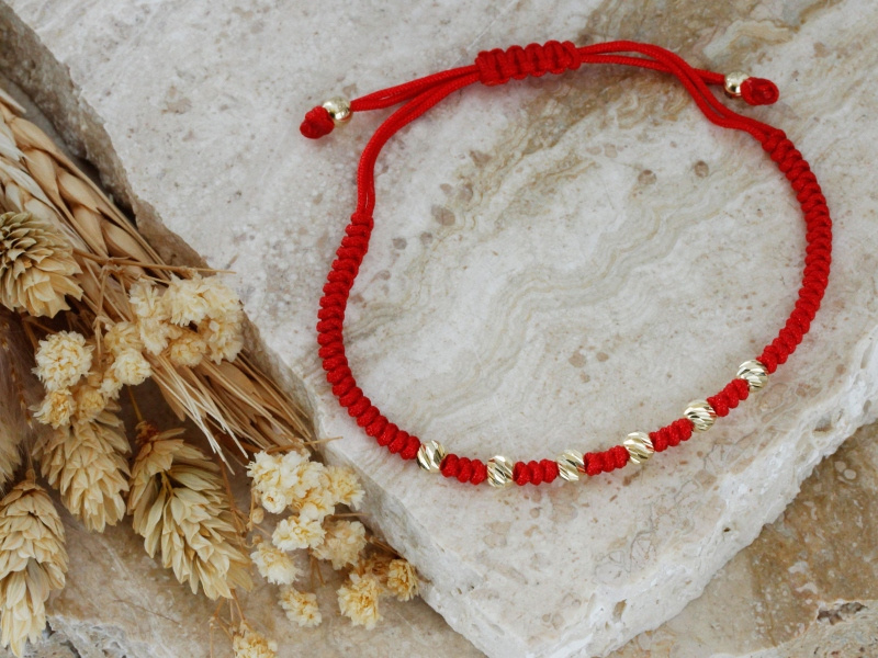 Złota bransoletka z diamentowanymi kulkami na czerwonym sznurku