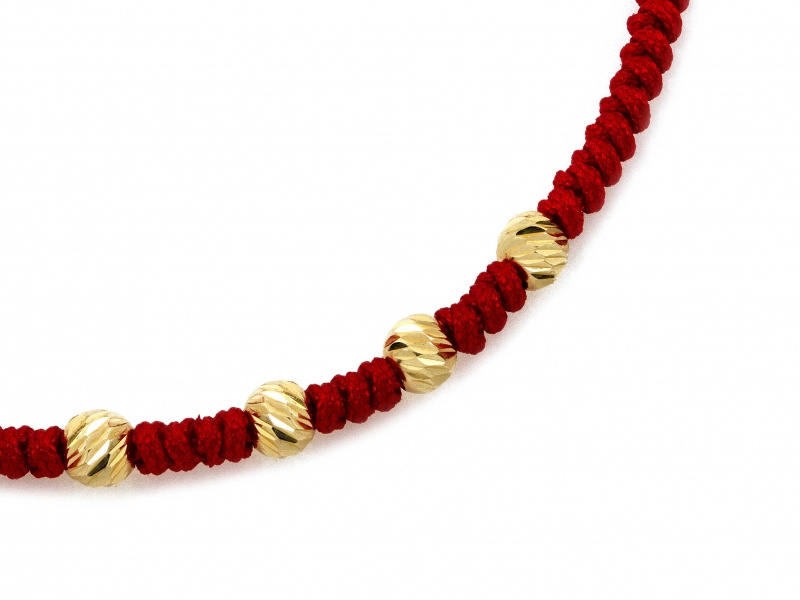 Złota bransoletka z diamentowanymi kulkami na czerwonym sznurku